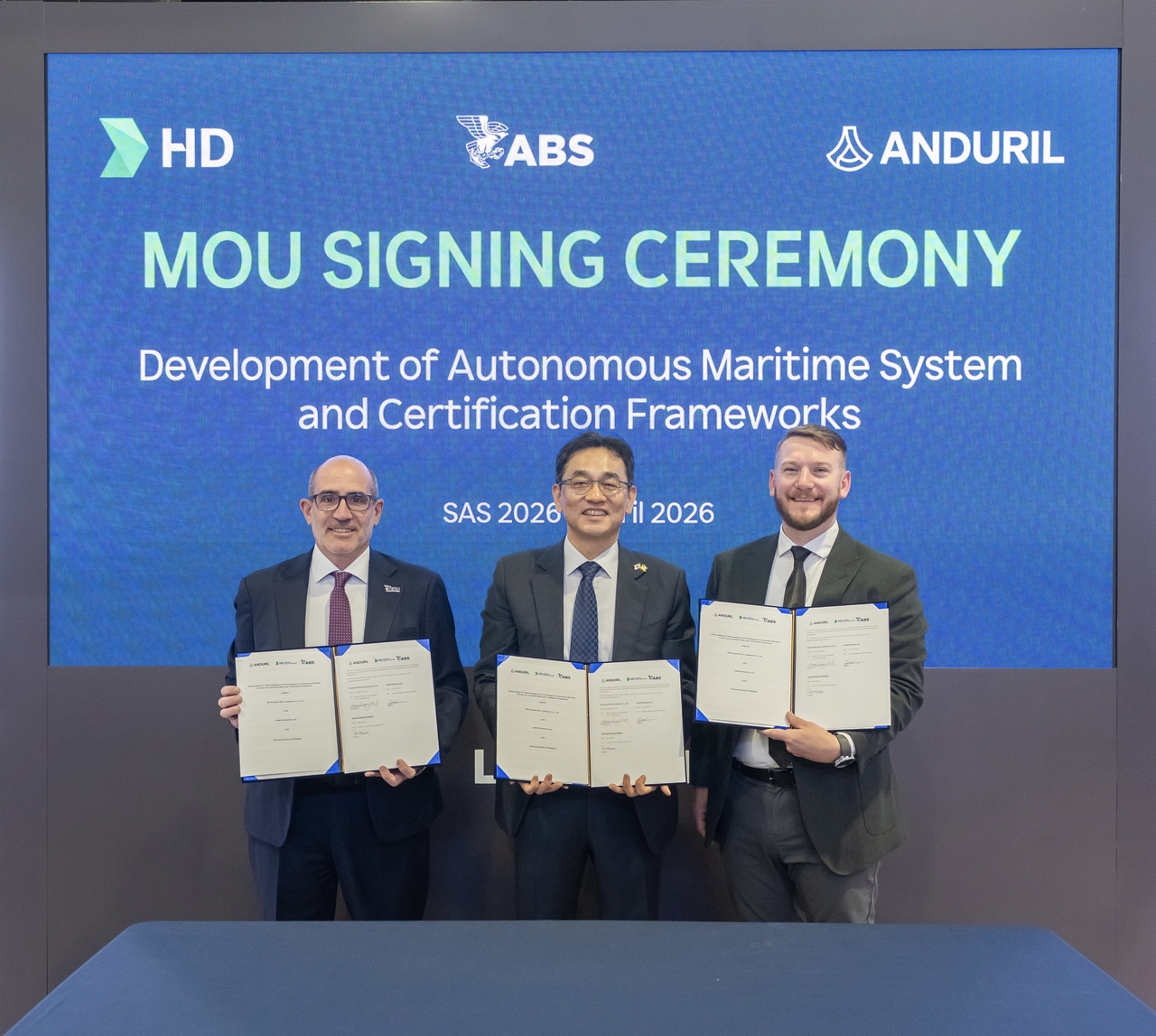 From left: Cory Emmons, general manager of Anduril Industries’ surface dominance division, Chang Kwang-pil, senior executive vice president and head of HD Korea Shipbuilding’s Future Technology Research Institute, and Paul Karam, executive vice president of American Bureau of Shipping, pose for a photo after signing a tripartite memorandum of understanding on Wednesday at SAS 2026 in Washington. (HD Hyundai)