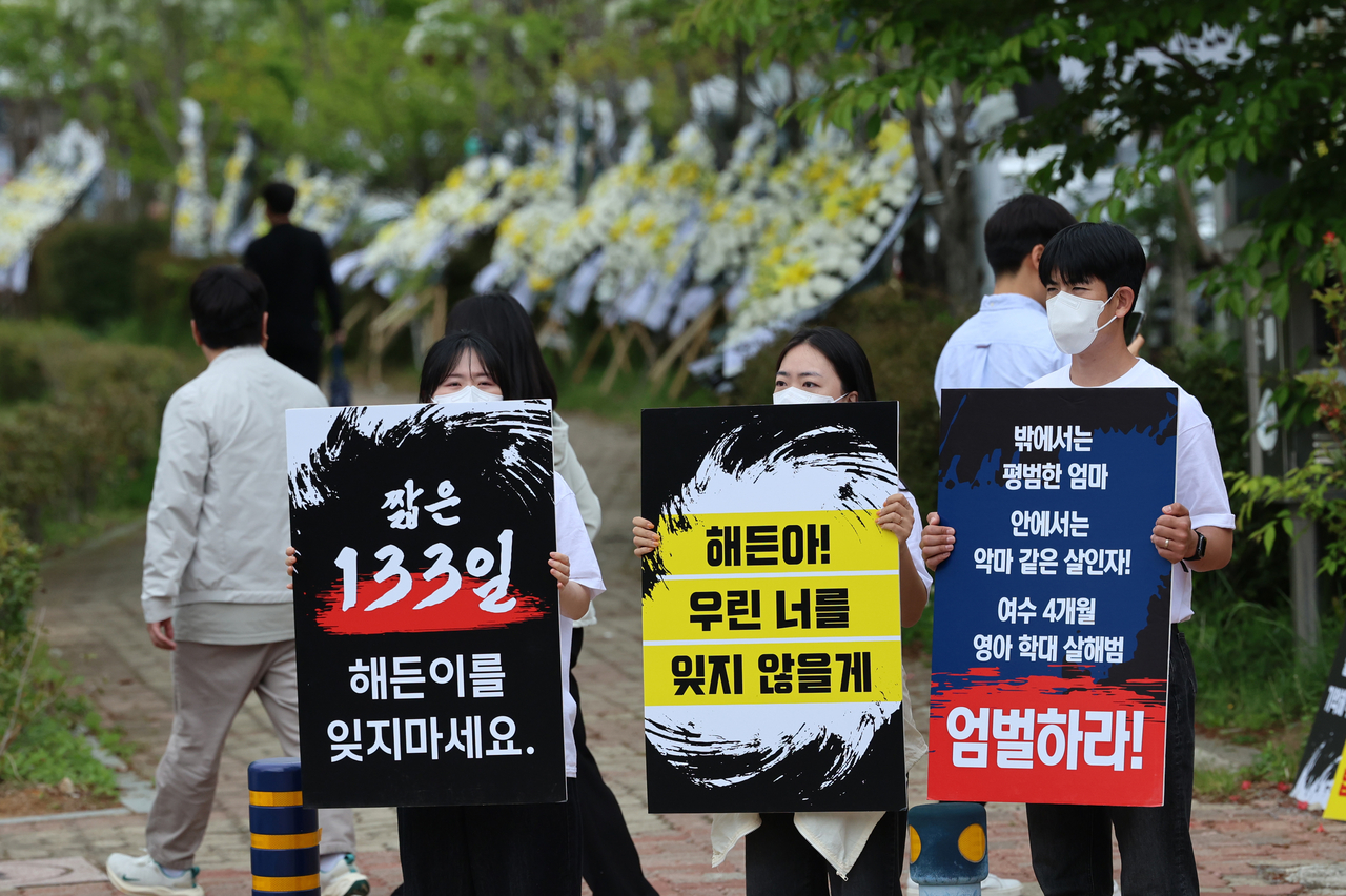 Protesters on Wednesday gather in front of the Gwangju District Court Suncheon Branch to urge the court to hand down a severe punishment for a mother who abused and murdered her 4-month-old son in 2025. Funeral flowers line the sidwalk. (Yonhap)