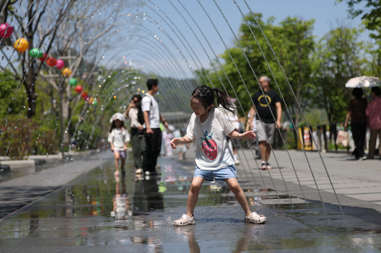 A child plays in the Gwanghwamun Square fountains in central Seoul on Sunday. (Yonhap)