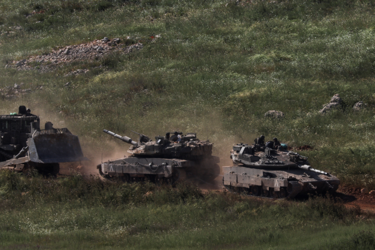 Tanks and an armoured vehicle drive in Lebanon, as seen from the Israeli side of the Israel-Lebanon border, in northern Israel, Saturday. Reuters-Yonhap