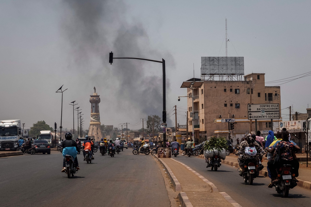 A column of black smoke rises above buildings as traffic passes the Africa Tower monument in Bamako, Mali, Sunday. (AFP-Yonhap)