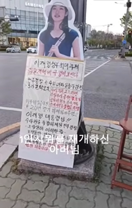 This screen capture, from a video about a man's protest to urge an investigation into his daughter's disappearance in 2006, shows the missing woman’s life-size cutout with the protester's message. (YouTube)