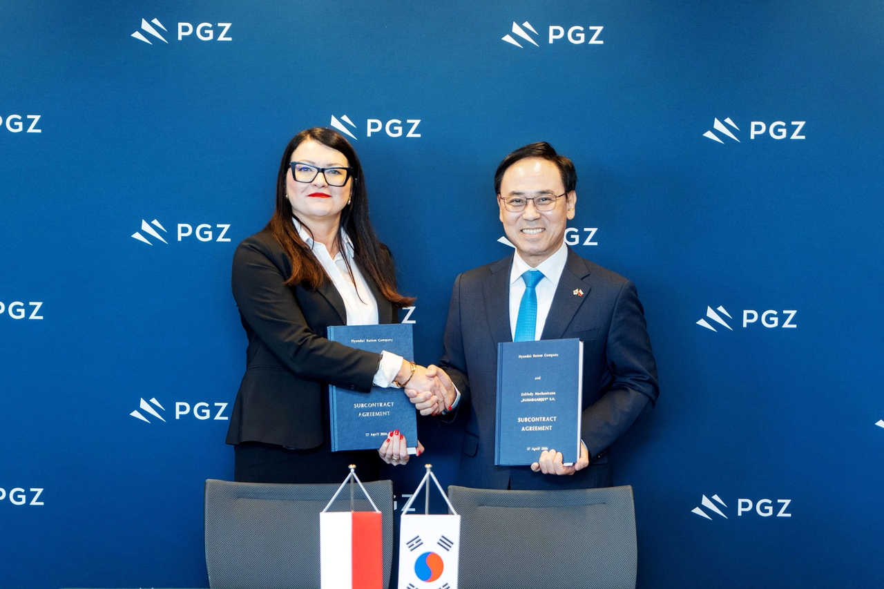 Lee Yong-bae (right), CEO of Hyundai Rotem, poses for a photo with Monika Kruczek, CEO of Bumar-Labedy, during a signing ceremony for a local production and maintenance cooperation agreement for the K2PL tank and armored recovery vehicles in Warsaw, Poland, Monday. (Hyundai Rotem)
