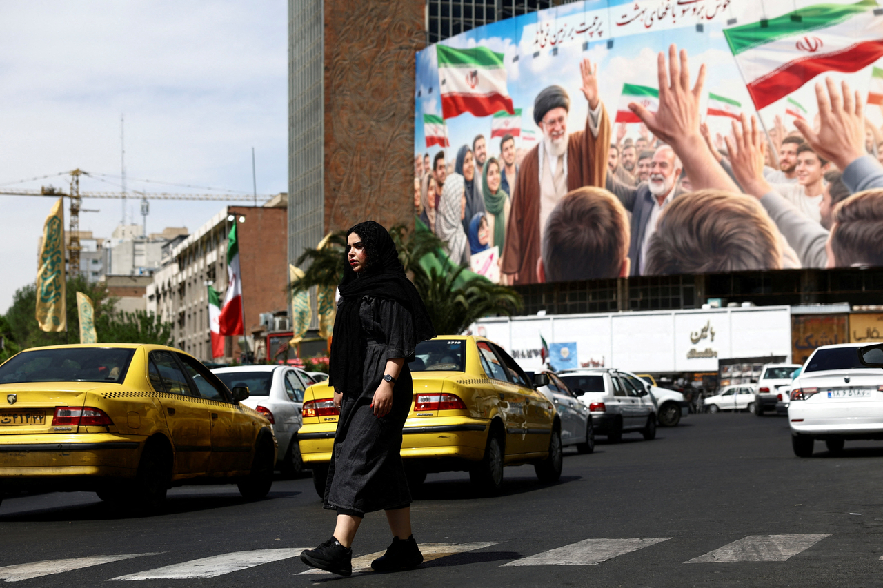 A woman walks past a billboard featuring an image of the late Supreme Leader of Iran, Ayatollah Ali Khamenei, in Tehran, Iran, Monday. (Reuters-Yonhap)