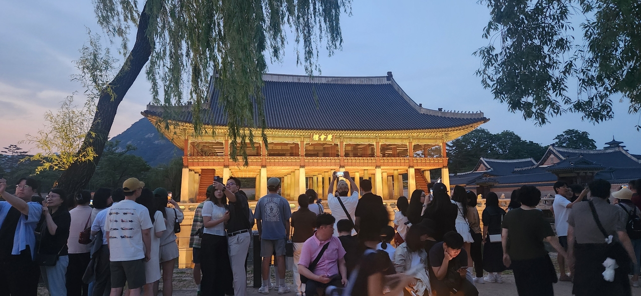 Visitors take photos during a nighttime tour of Gyeongbokgung in 2025. (Korea Heritage Service)