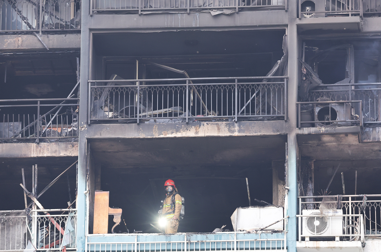 A firefighter inspects the scene of a fire at an apartment building in Uiwang, Gyeonggi Province, Thursday. (Yonhap)