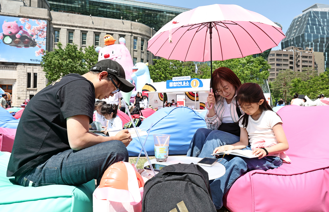 Visitors settle into beanbags with books at Seoul Plaza on Friday, the first day of the venue's opening as part of the city's outdoor library program. (Yonhap)