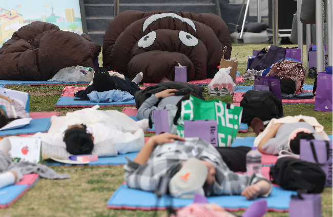 Participants dressed in poop-shaped costumes sleep during the Hangang Nap Competition at Yeouido Hangang Park  on Saturday. (Yonhap)