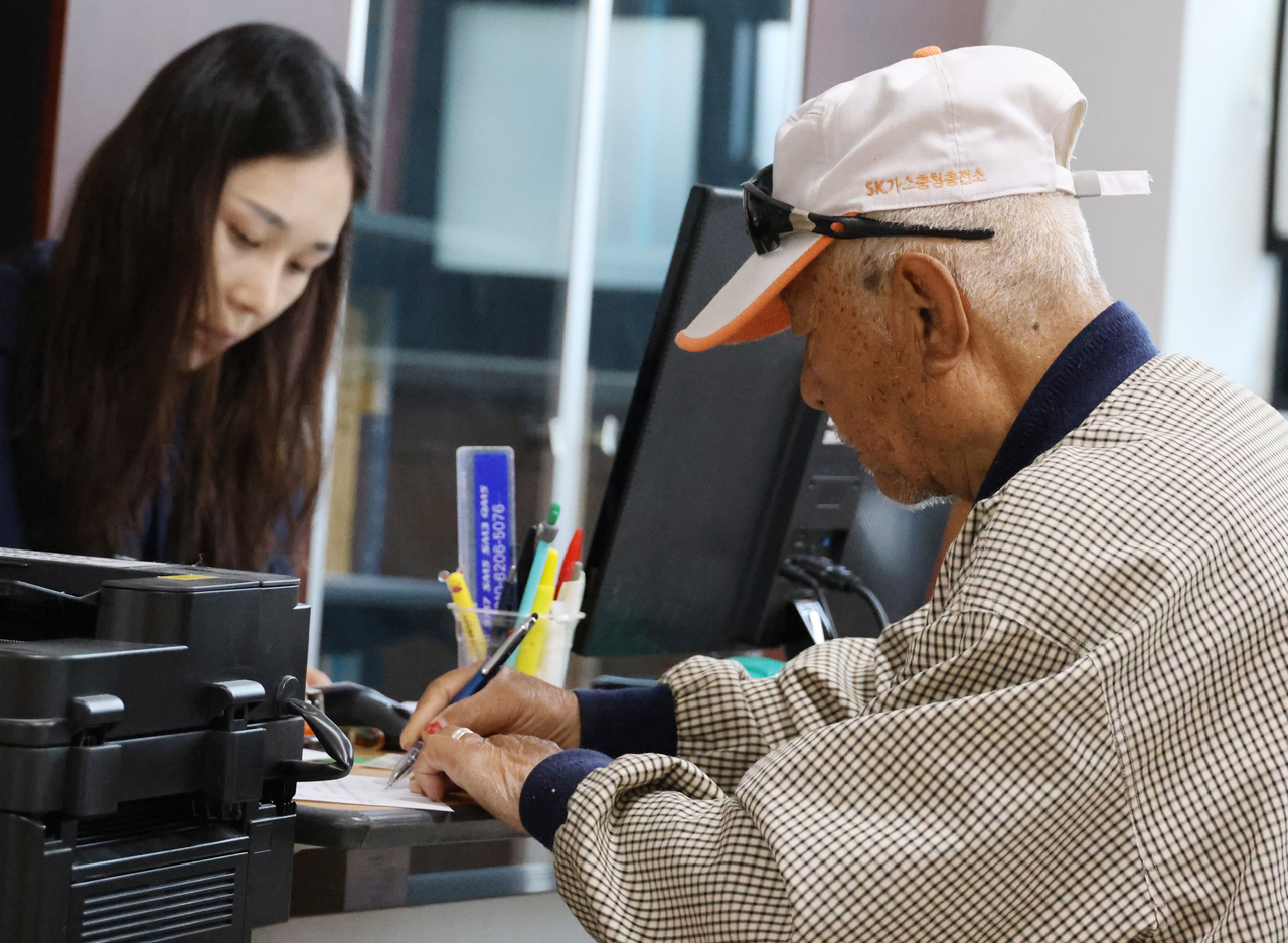 A pensioner fills out a form at a welfare center in Cheongju, North Chungcheong Province, to apply for a government stipend on April 27. (Yonhap)