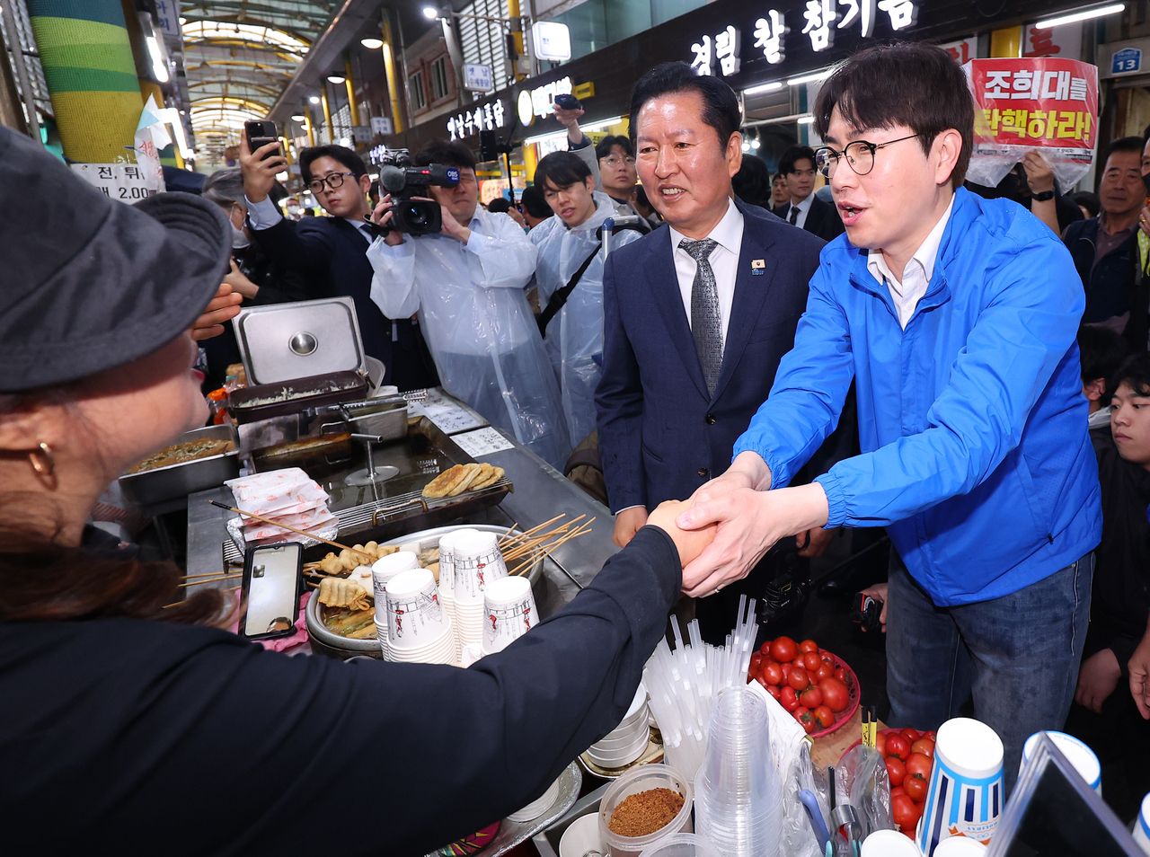 Former senior presidential secretary Ha Jung-woo (right) and Democratic Party chair Rep. Jung Chung-rae (second from left) are seen during their visit to a traditional market in Busan on Sunday. (Yonhap)