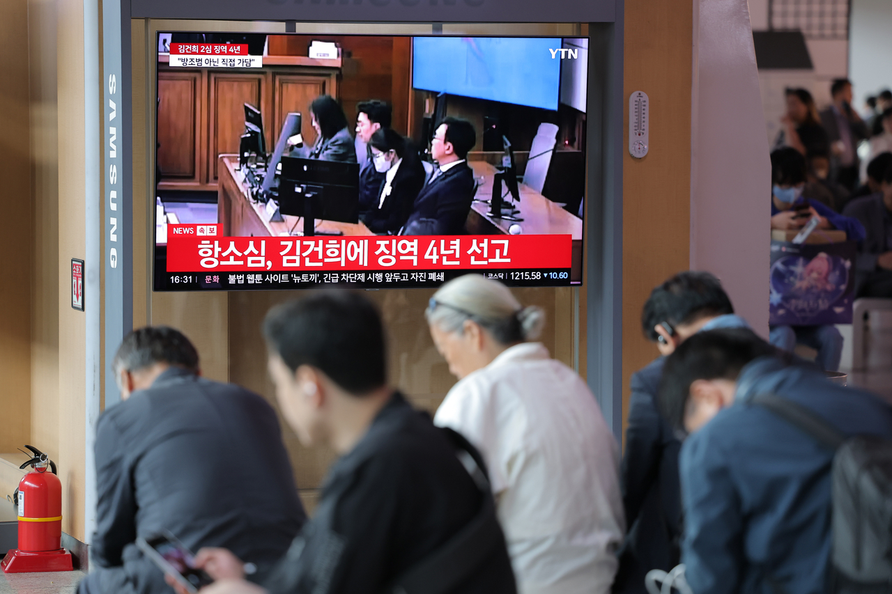 People at Seoul Station watch the televised appellate ruling of former first lady Kim Keon Hee's bribery and stock manipulation charge on Tuesday. (Yonhap)