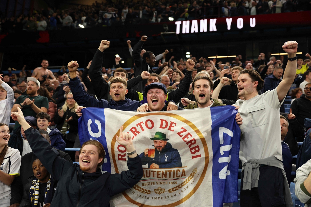 Fans hold up a flag with Tottenham Hotspur's Italian head coach Roberto De Zerbi as they celebrate the team's victory against Aston Villa, at Villa Park in Birmingham, England, Sunday.    (AFP-Yonhap)