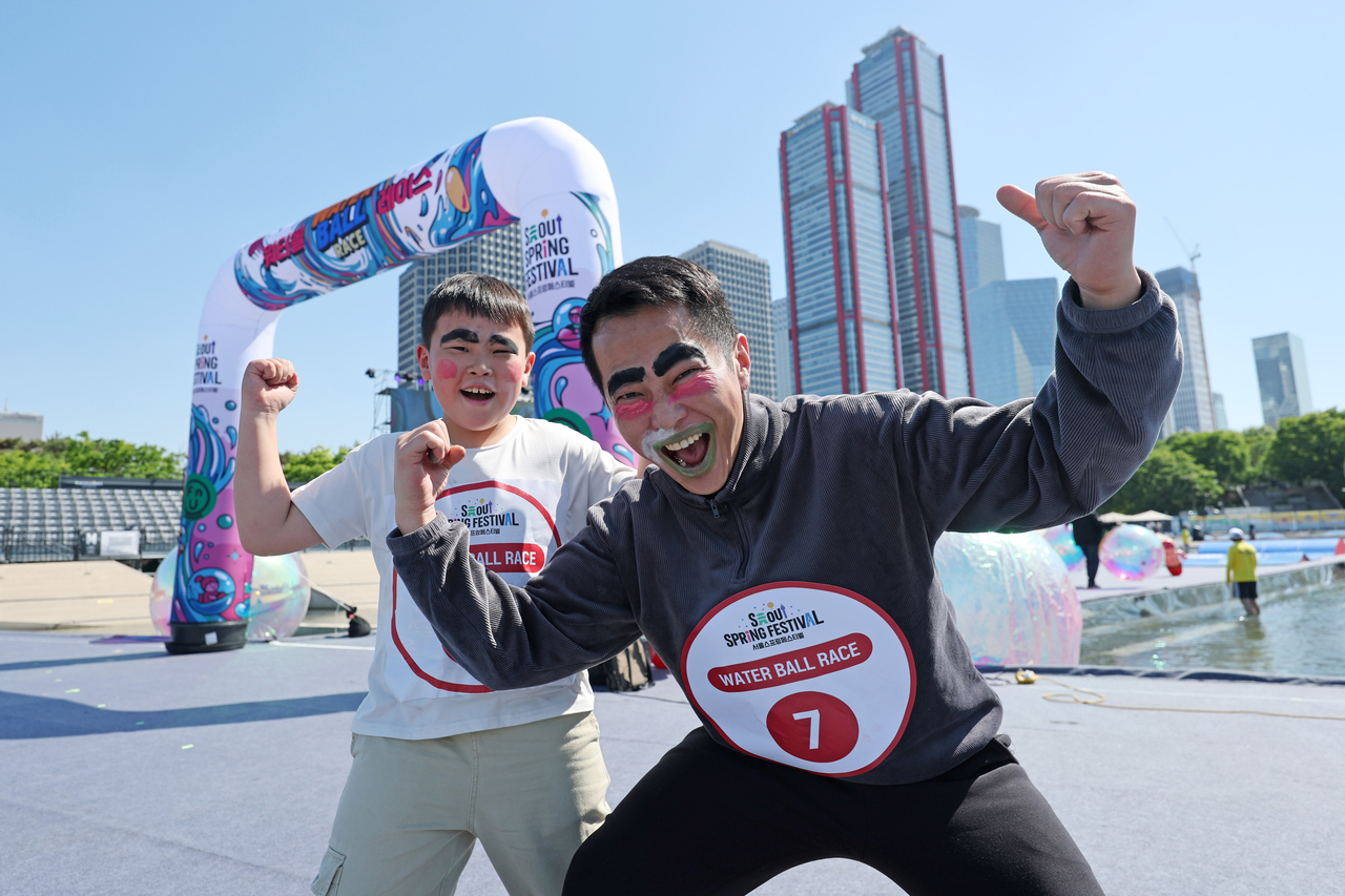 A father and son cheer after finishing the "Water Ball Race" at Yeouido Hangang Park in Seoul on Children's Day. (Yonhap)