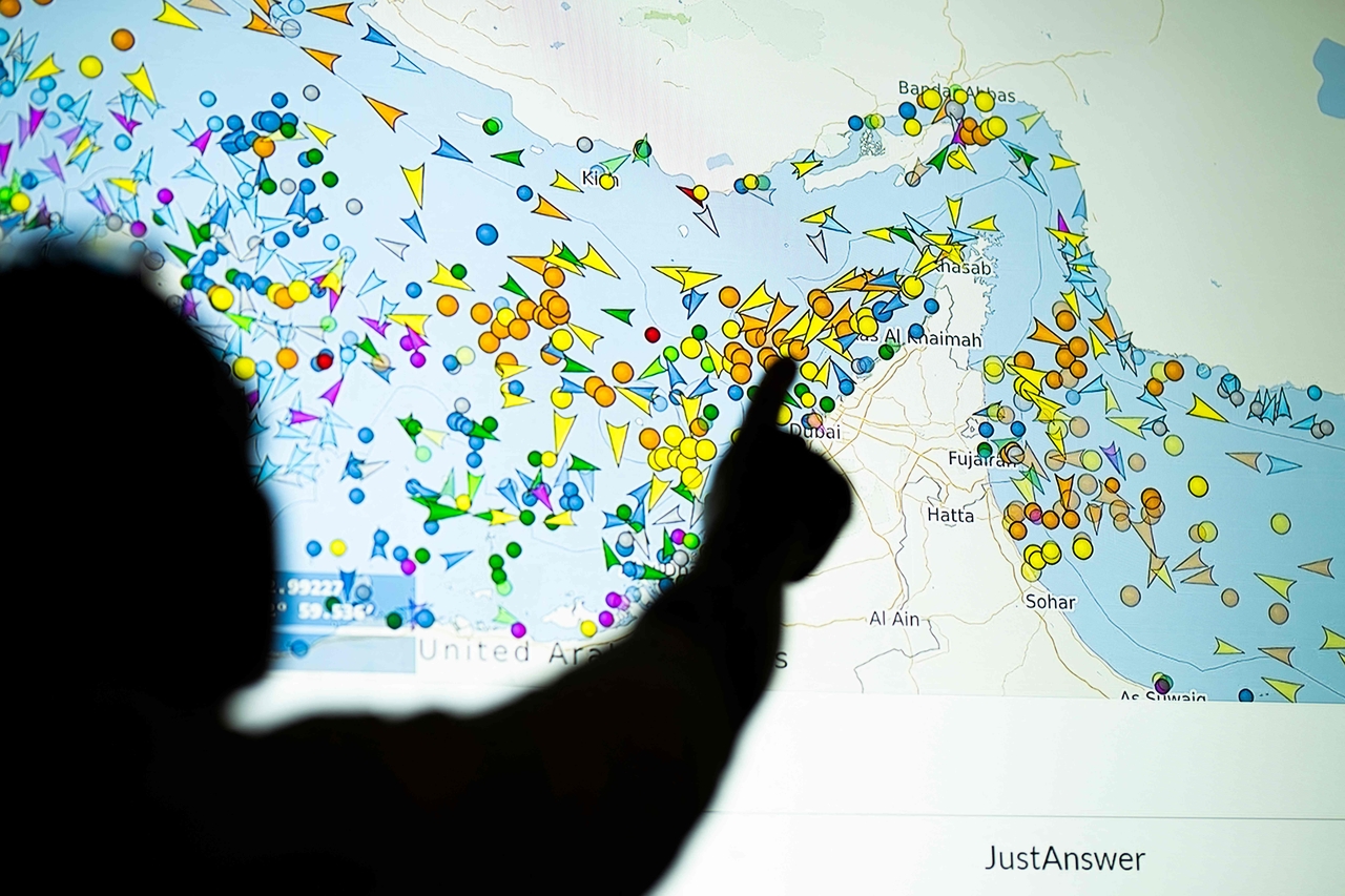 A photo illustration taken in Nicosia on Monday shows a person in front of a large screen displaying vessel movements in the Strait of Hormuz on a ship-tracking website. (AFP-Yonhap)
