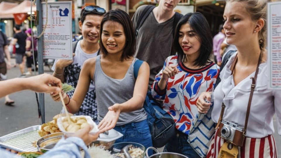 Tourists enjoy Vietnamese street food at a bustling market in Ho Chi Minh City, reflecting the growing appeal of culinary tourism.    (Viet Nam News)