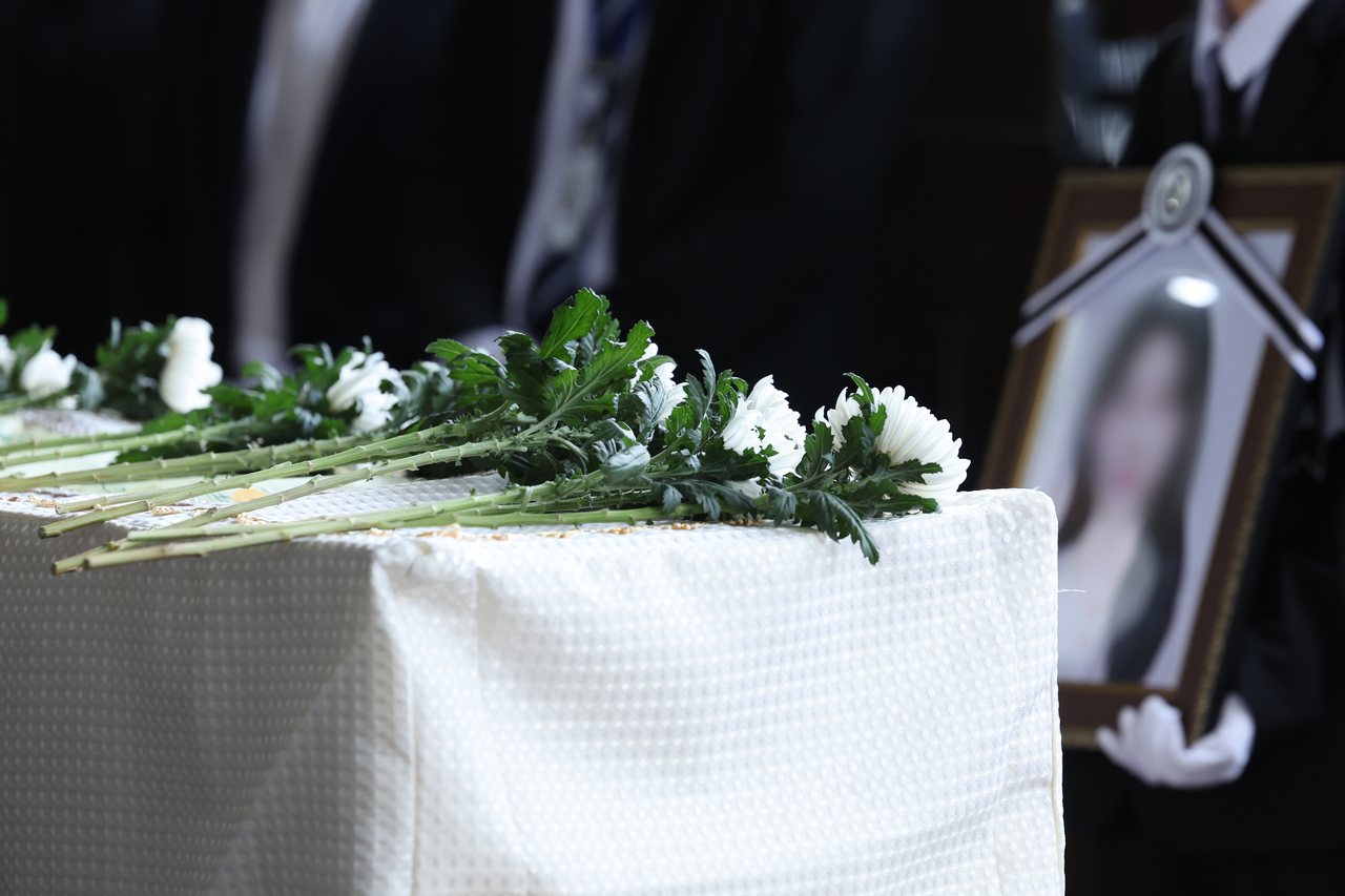 White chrysanthemums rest atop the coffin of a high school girl fatally stabbed by a 24-year-old man during her funeral procession in Gwangsan-gu, Gwangju, on Thursday. (Yonhap)