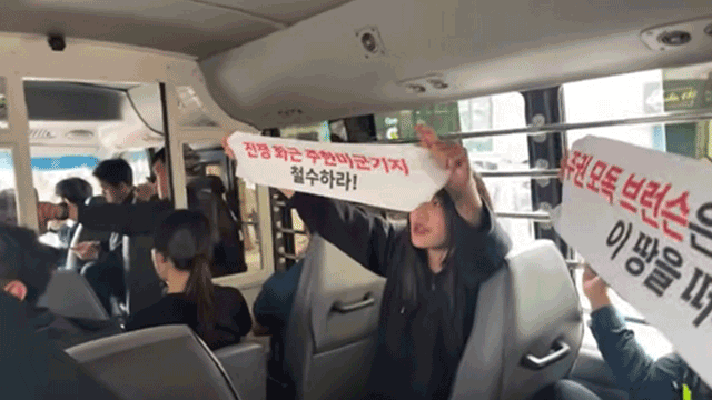 Protesters hold banners condemning the US while being taken to a police station in central Seoul on Thursday. (Korean Progressive University Student Union's YouTube channel)