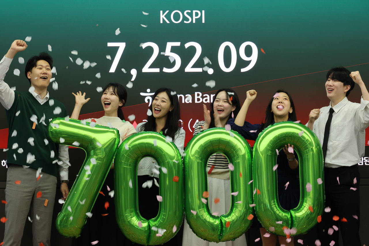 Hana Bank dealers celebrate the Kospi's rise above 7,000 for the first time at a dealing room in Seoul on Wednesday morning. (Yonhap)