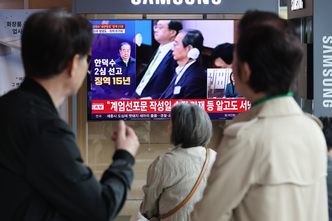 Citizens watch a live broadcast of the appeals court ruling on former Prime Minister Han Duck-soo at Seoul Station in central Seoul on Thursday. (Yonhap)