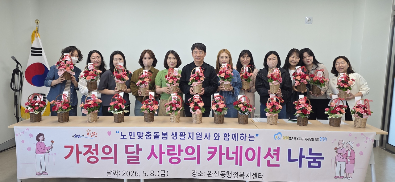 완산동 관계자와 노인맞춤돌봄서비스 생활지원사들이 어르신들께 전달할 카네이션과 함께 기념촬영을 하고 있다.[영천시 제공]