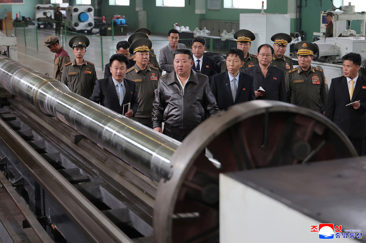 North Korean leader Kim Jong-un (front) inspects materials at a major munitions factory Wednesday, alongside North Korean officials, in this photo released by the Korean Central News Agency on Friday. (KCNA via Yonhap)