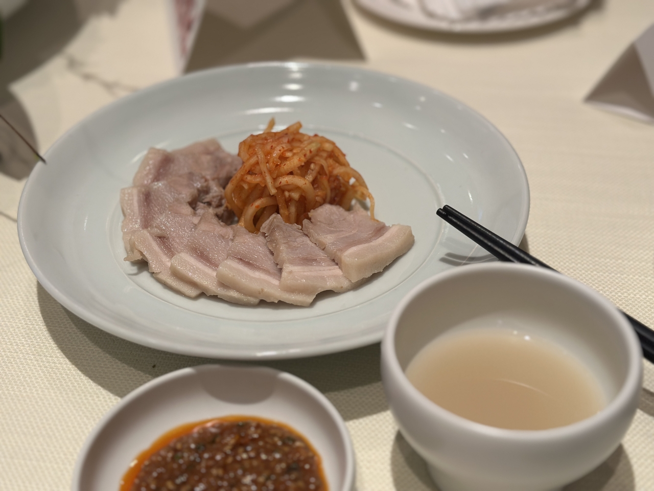 Boiled pork slices, spicy radish salad and ssamjang paired with Yun Judang Takju 12 (Tammy Park/The Korea Herald)