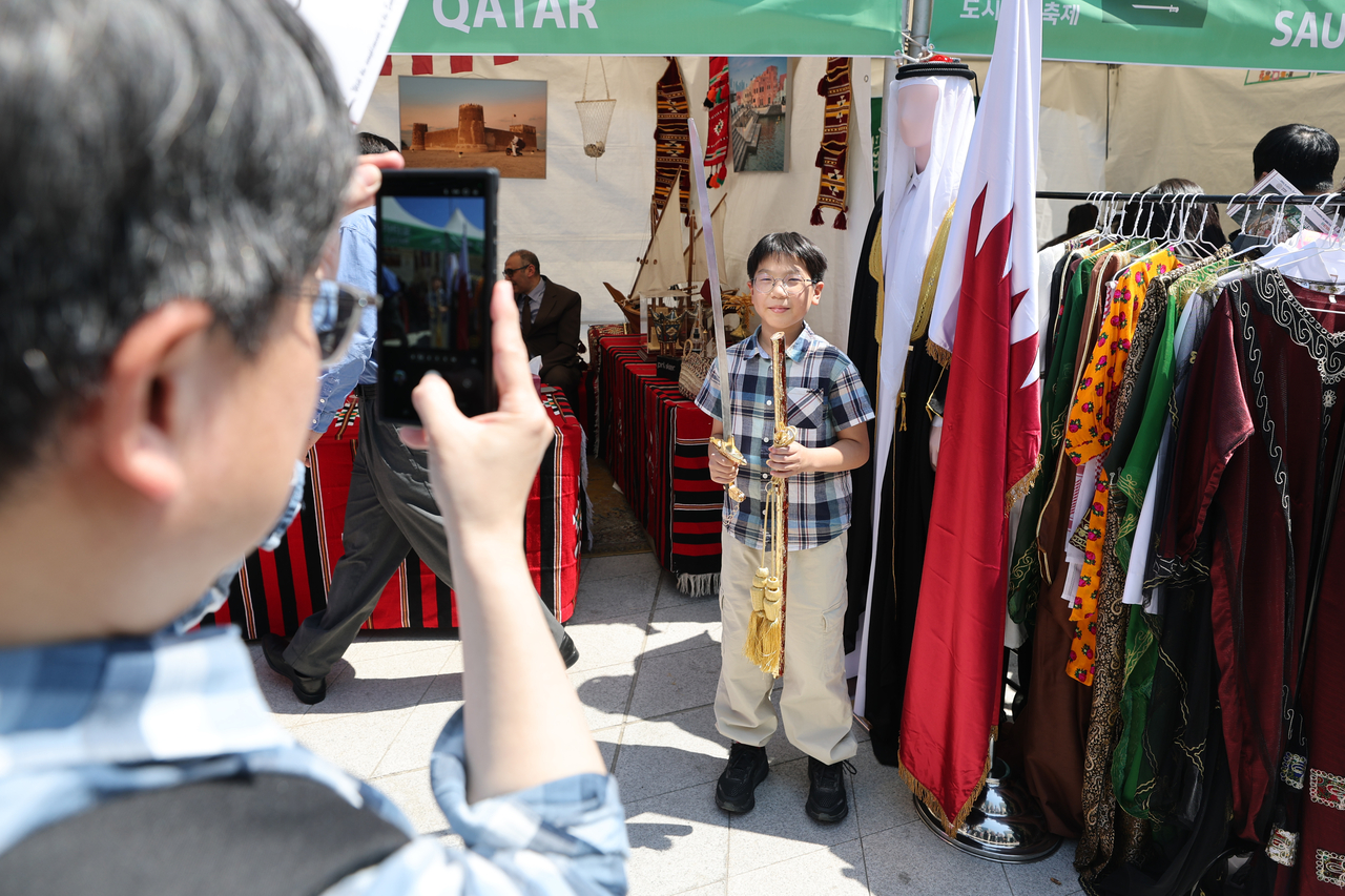 A child poses for a photo while holding a sword at the Qatar booth during the Seoul Friendship Festival at Dongdaemun Design Plaza on Saturday. (Yonhap)
