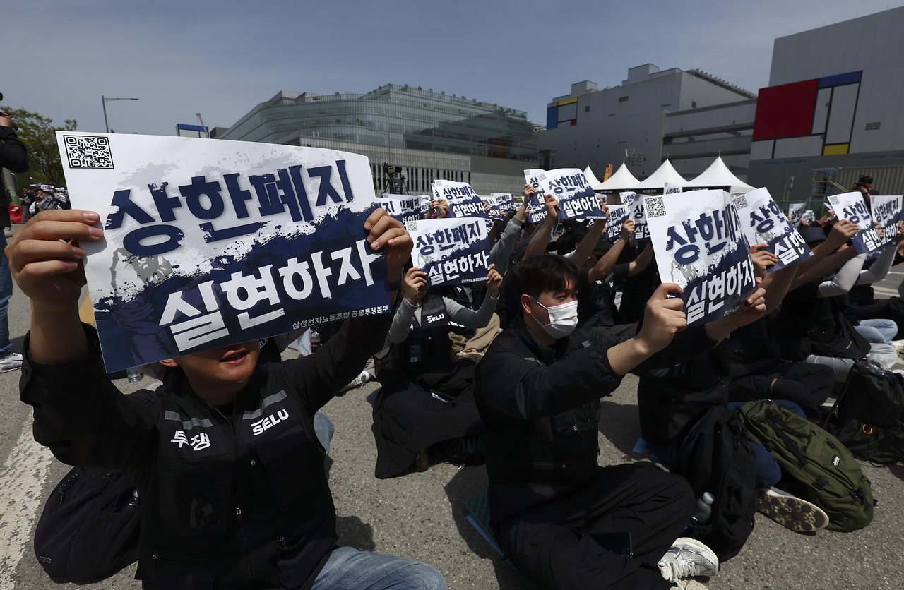Members of Samsung Electronics' union coalition hold up placards reading 