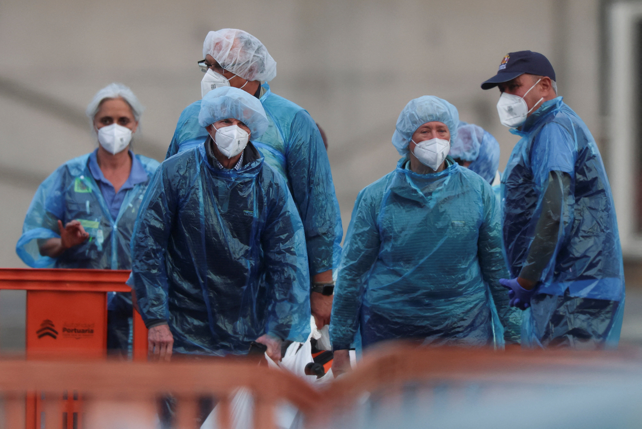 US passengers from the cruise ship MV Hondius, affected by a hantavirus outbreak, stand on land after disembarking the ship, at the port of Granadilla de Abona, in Tenerife, Spain, Sunday. (Reuters-Yonhap)