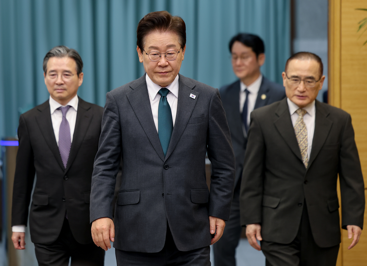 President Lee Jae Myung (second from left) walks with chief presidential secretary for policy Kim Yong-beom (left) in Cheong Wa Dae on May 7. (Yonhap)