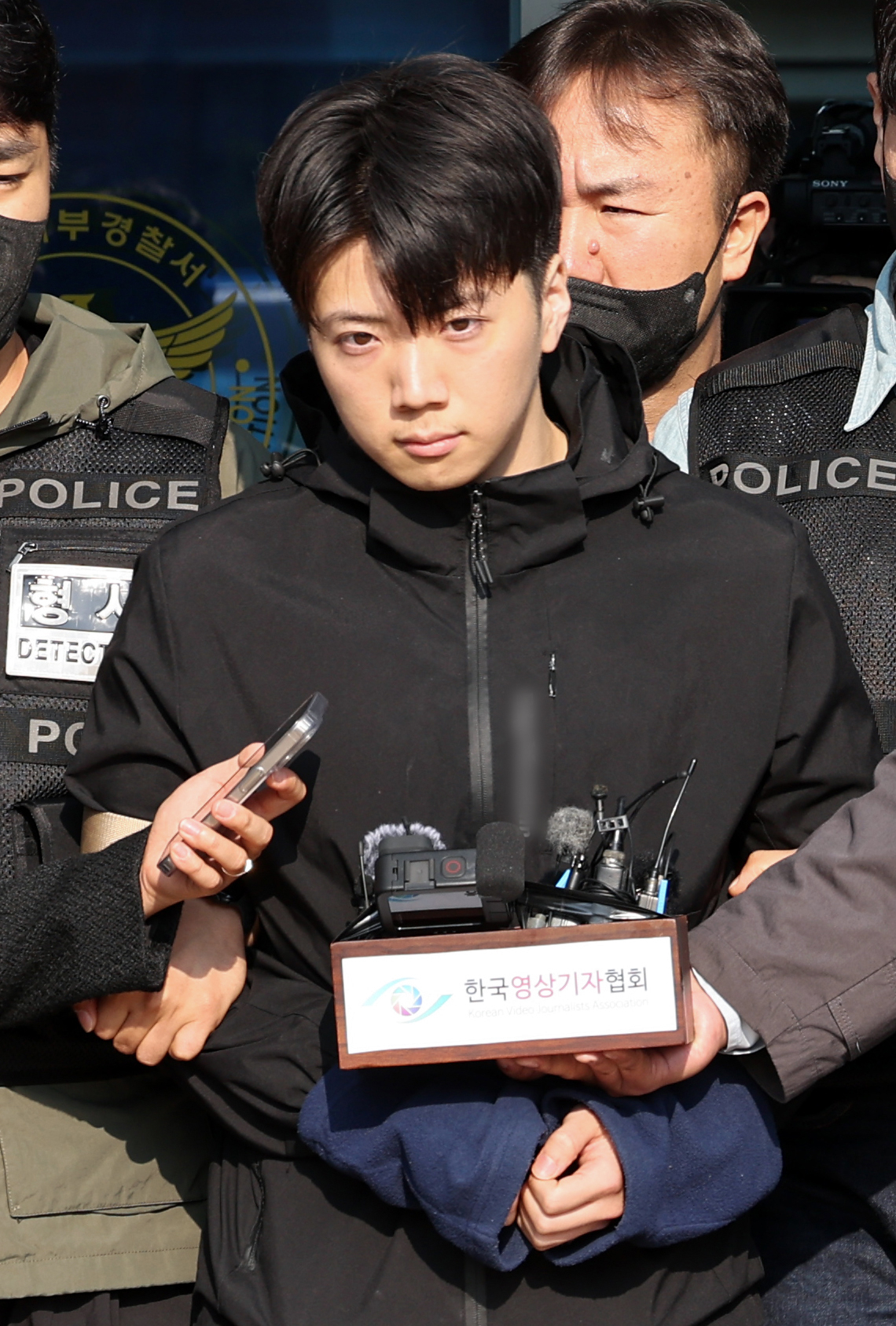 Jang Yoon-ki, accused of murdering a female high school student and injuring a male student, is escorted out of the Gwangju Seobu Police Station on Thursday. (Yonhap)