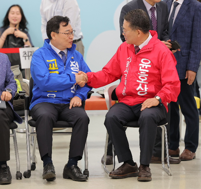 Liberal Seoul superintendent candidate Jung Geun-sik (left) and conservative candidate Yoon Ho-sang, who both emerged as winners in their respective primaries, shake hands ahead of their candidacy registrations on Thursday. (Yonhap)