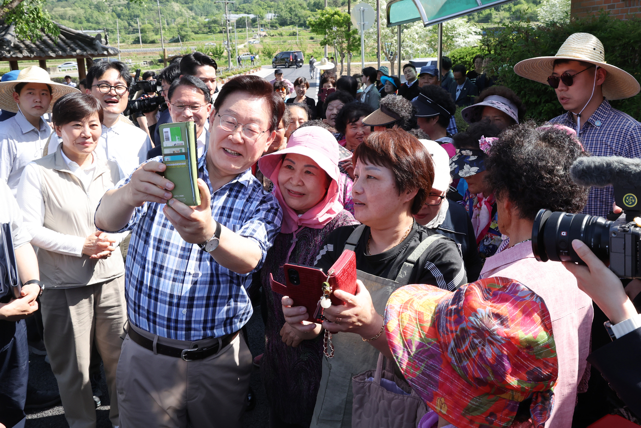 South Korean President Lee Jae Myung poses for a  photo with residents ahead of a rice planting in Sobo Myeon, Gunwi County, Daegu, Friday. (Yonhap)