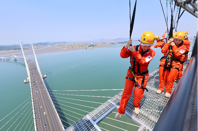 Visitors at Incheon’s Cheongna Sky Bridge Observatory in Incheon enjoy the new Edge Walk experience on Friday, the day of the program's launch. (Yonhap)