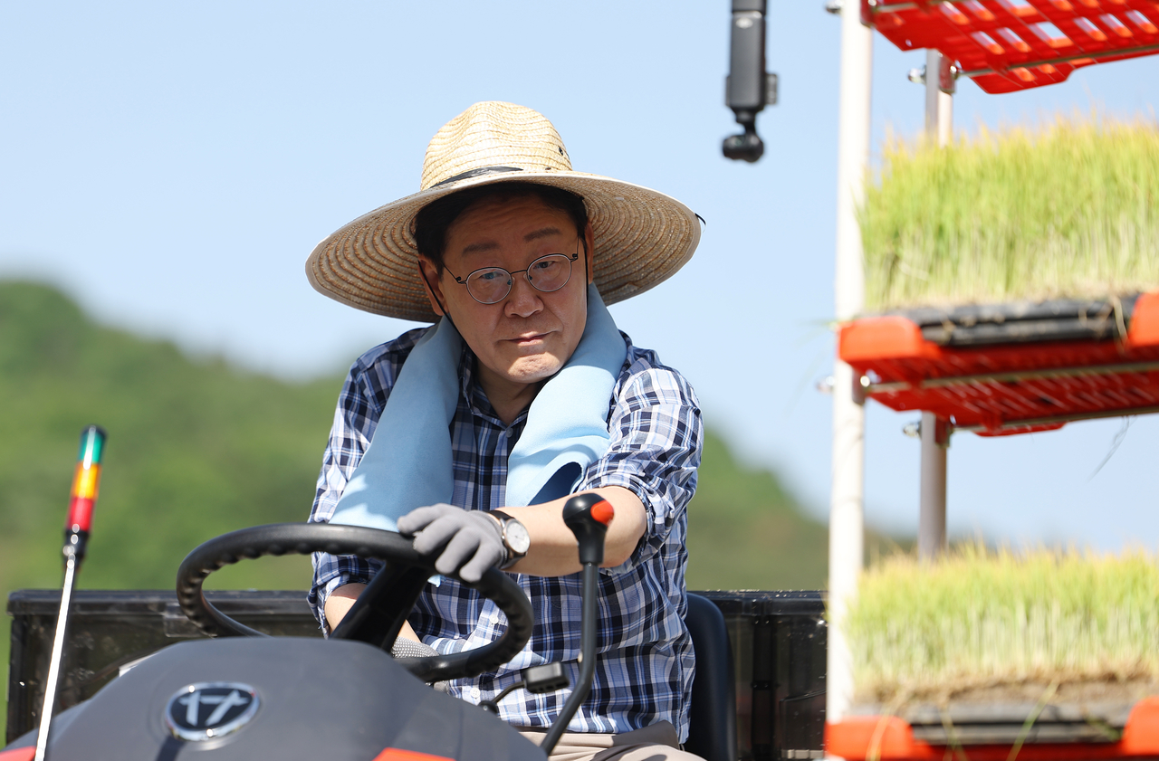 South Korean President Lee Jae Myung operates a rice transplanter during a rice planting in Sobo Myeon, Gunwi County, Daegu, Friday. (Yonhap)