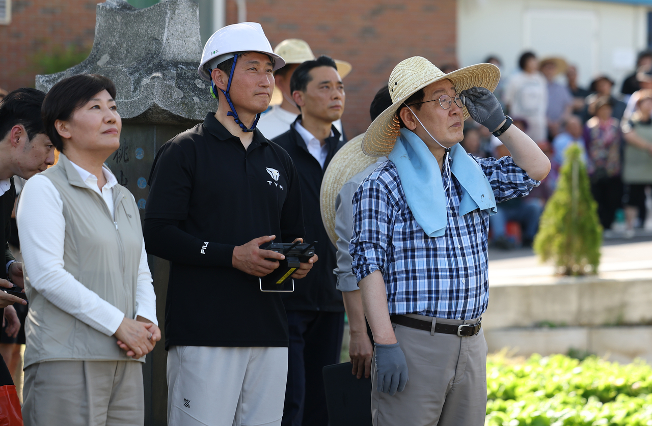 South Korean President Lee Jae Myung observes a drone-based pesticide spraying demonstration during a rice planting event in Sobo Myeon, Gunwi County, Daegu, Friday. (Yonhap)