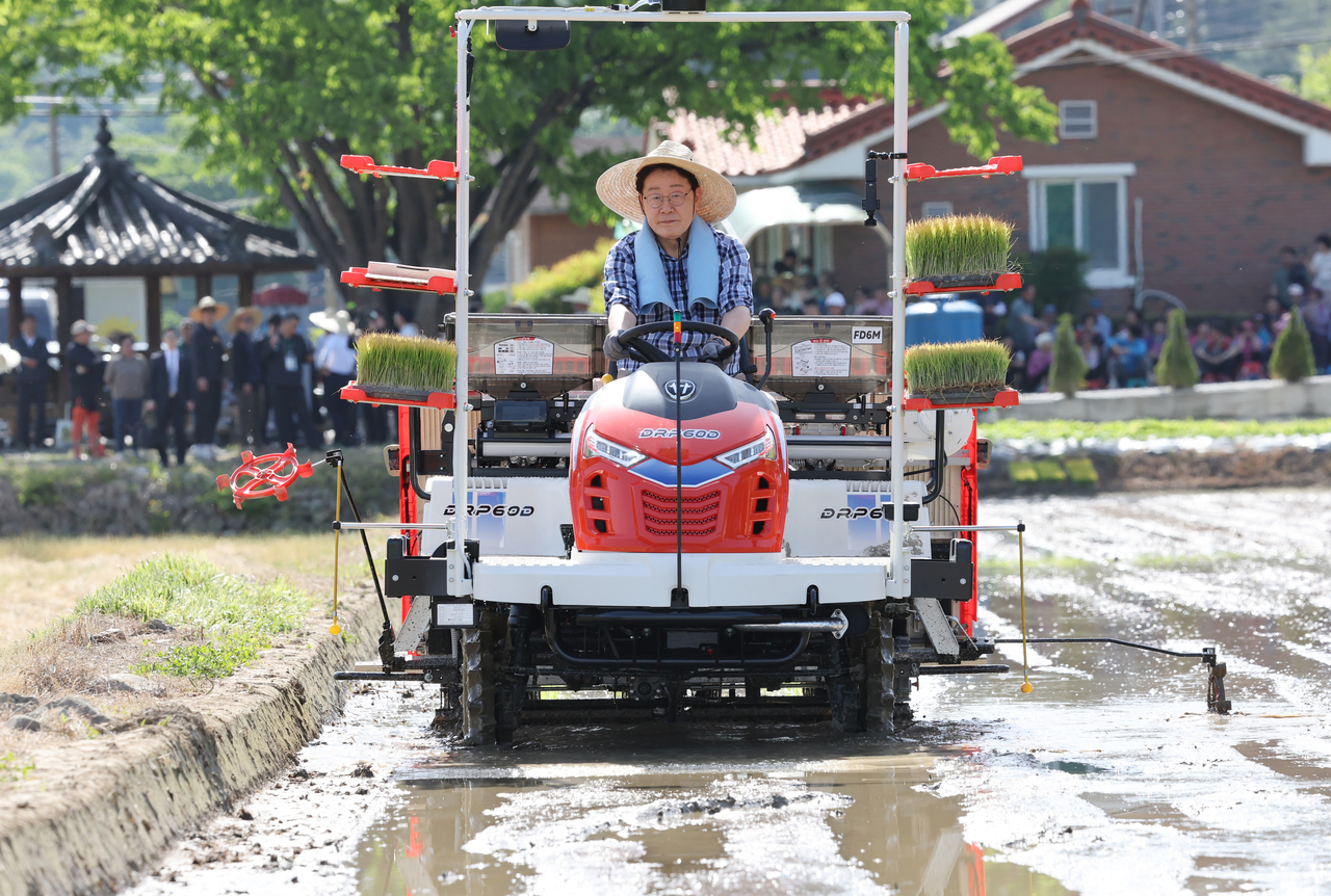 South Korean President Lee Jae Myung operates a rice transplanter during a rice planting in Sobo Myeon, Gunwi County, Daegu, Friday. (Yonhap)