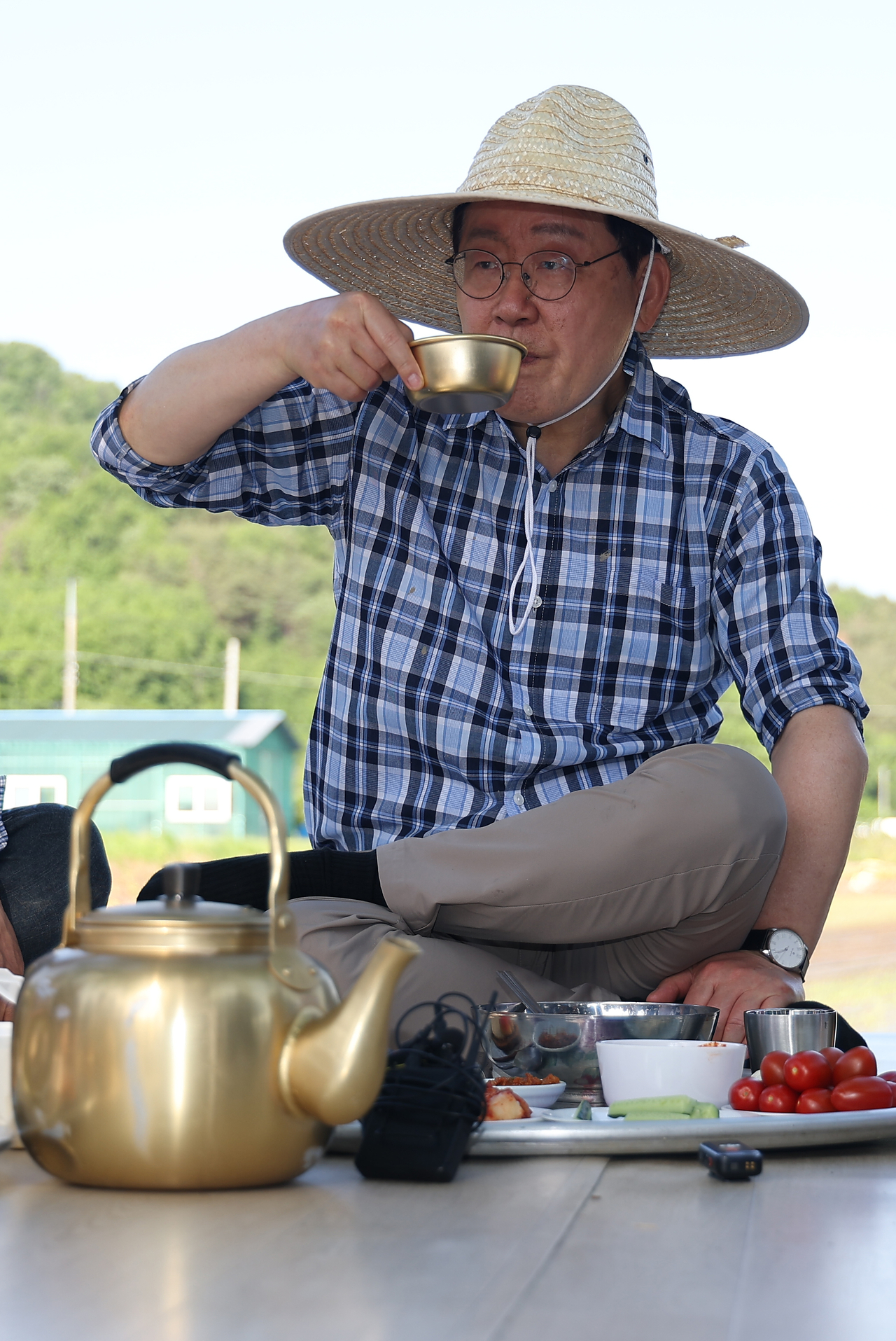 South Korean President Lee Jae Myung shares “saecham,” a traditional farm break meal, with residents after rice planting in Sobo Myeon, Gunwi County, Daegu, Friday. (Yonhap)
