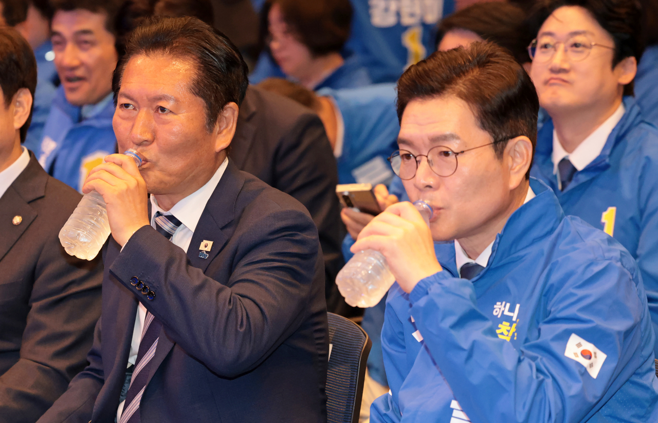 Rep. Jung Chung-rae (left), chair of the ruling Democratic Party of Korea, drinks water alongside the party’s Seoul mayoral candidate Chong Won-o during a candidate meeting in Seoul on May 11. (Joint Press Corps via Yonhap)