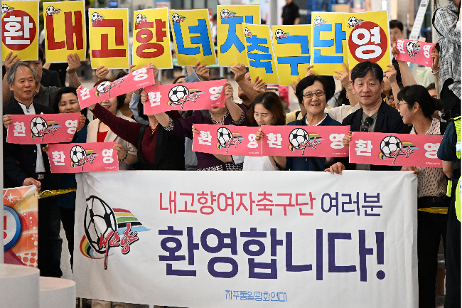 Supporters from local civic groups hold placards welcoming the North Korean women’s football team at Incheon International Airport on Sunday. (Joint Press Corps via Yonhap)