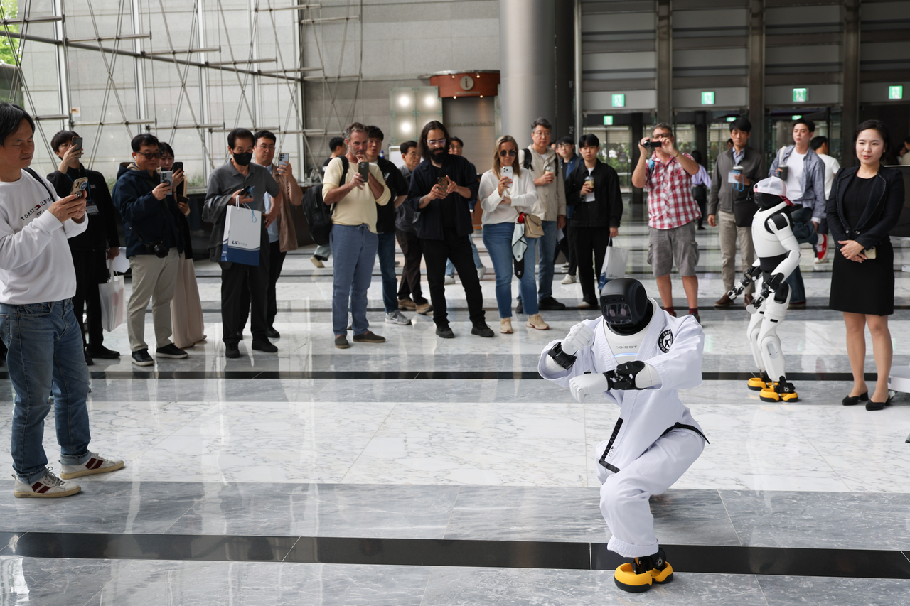Visitors take pictures of a humanoid robot dancing inside the COEX convention center in southern Seoul, in this file photo taken April 7, 2026. (Yonhap)
