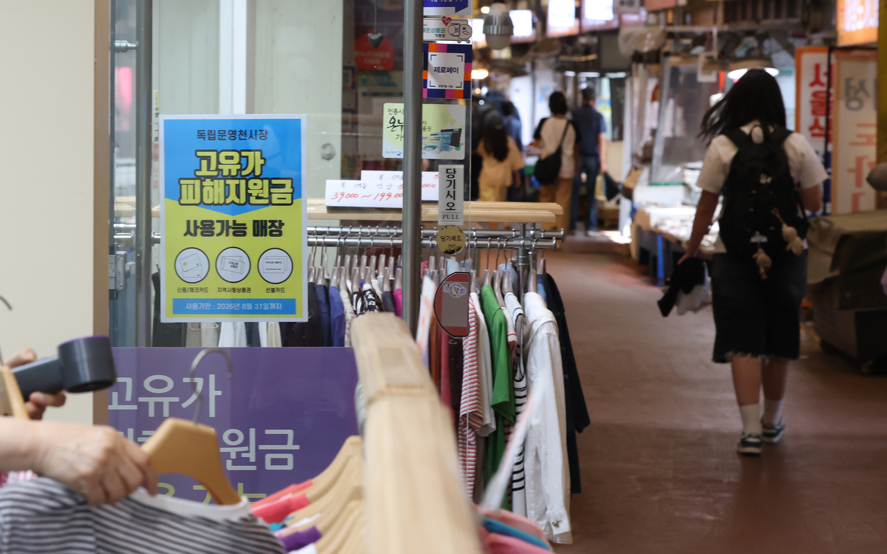 A person walks by a store with a sign saying it accepts government cash aid amid the Middle East crisis at a traditional market in western Seoul on Sunday. (Yonhap)