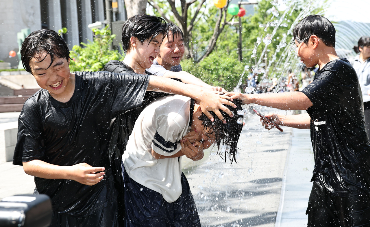 Students cool off in a fountain tunnel at Gwanghwamun Square in Seoul on May 17, as daytime temperatures rose, bringing summer-like heat to the capital. (Yonhap)