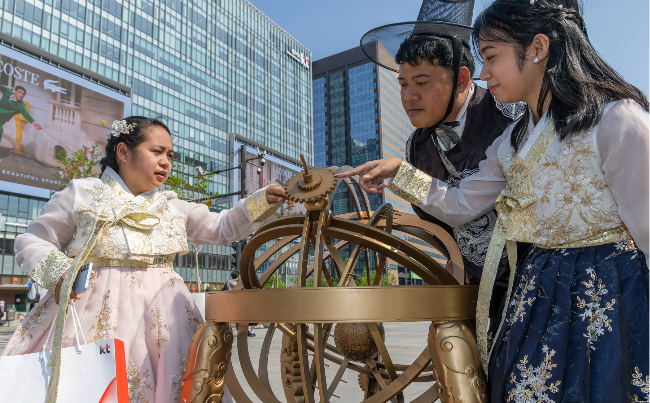 Curiba Ma Jo-velle (left), her husband and their daughter look at a replica of a Joseon-era sundial displayed at Gwanghwamun Square in central Seoul during a visit arranged through a KT event for foreign customers. (KT)