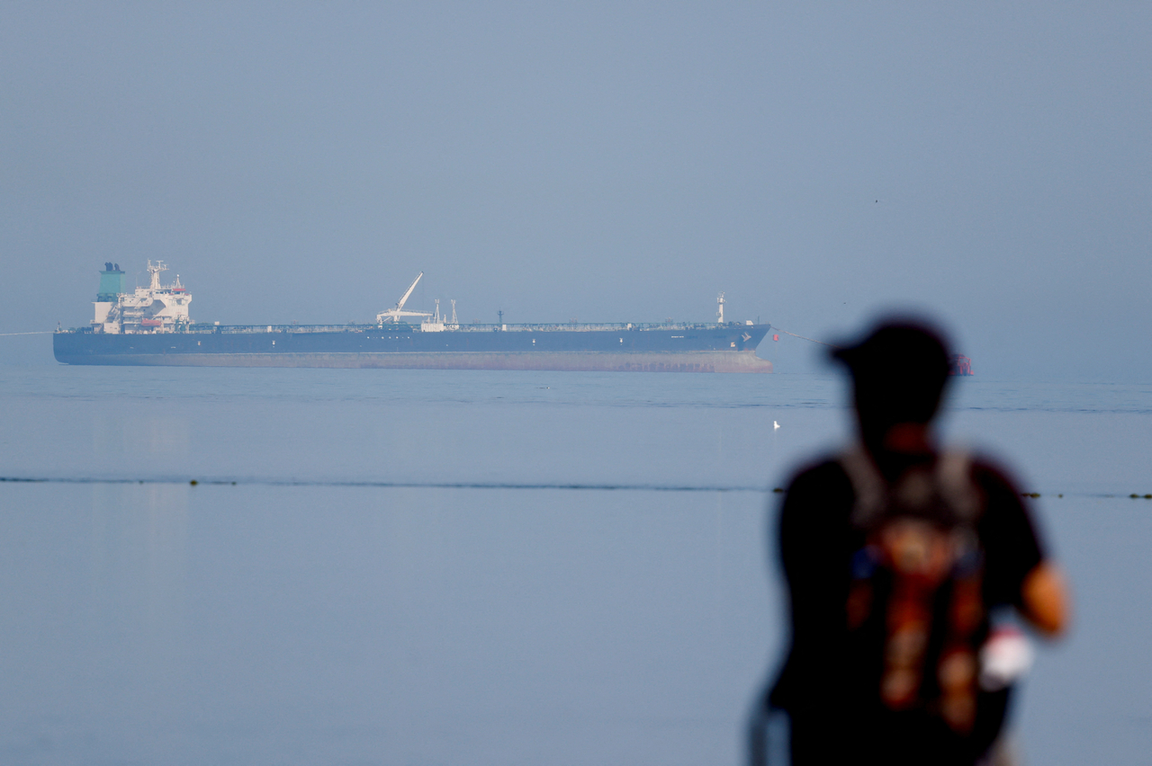 A tourist watches the MT Desert Kite oil tanker carrying Russian oil at Narara Marine National Park in the Arabian Sea, Gujarat, India, March 11.   Reuters-Yonhap