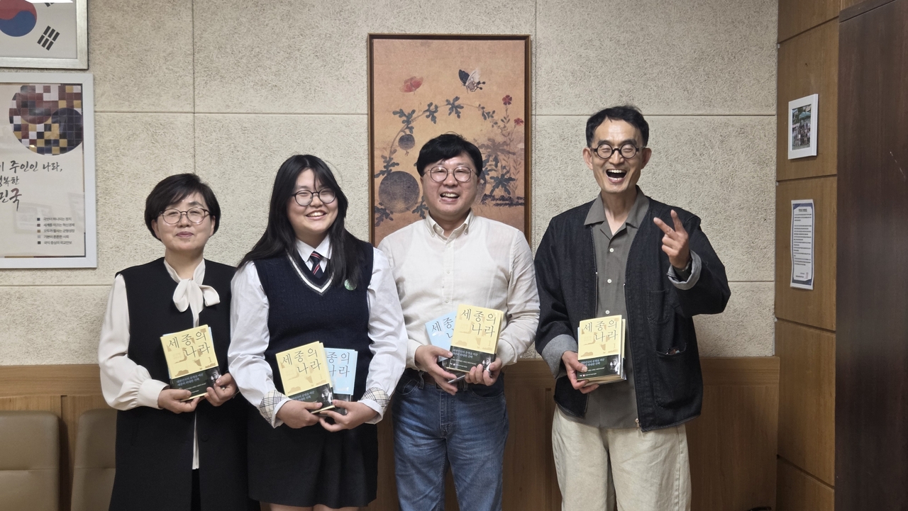 유동숙(왼쪽) 장안여중 교장이 학생, 선생님들과 함께 역사 대하소설 ‘세종의 나라’를 들고 기념촬영을 하고 있다.  [이타북스 제공]