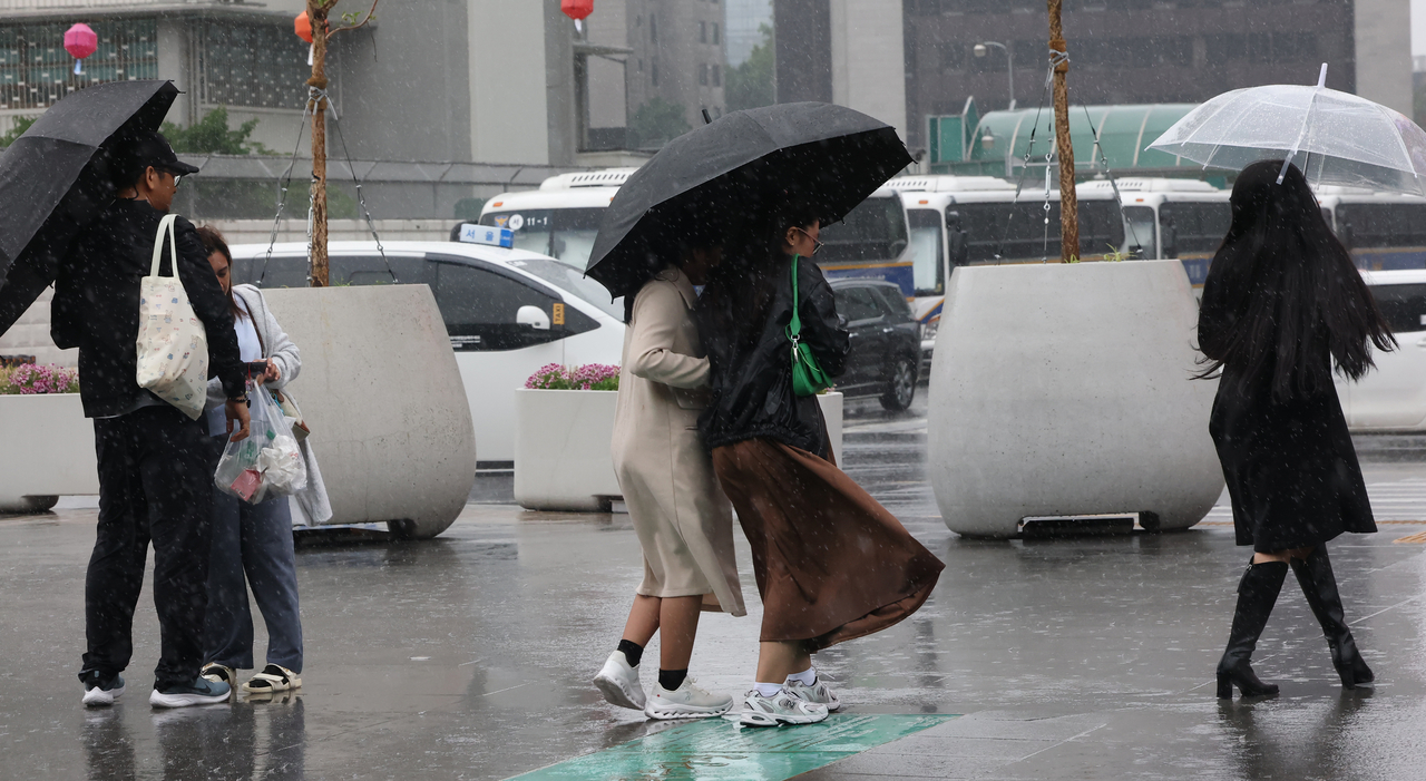Pedestrians walk through strong wind and rain near Gwanghwamun Square in central Seoul on Tuesday. (Yonhap)