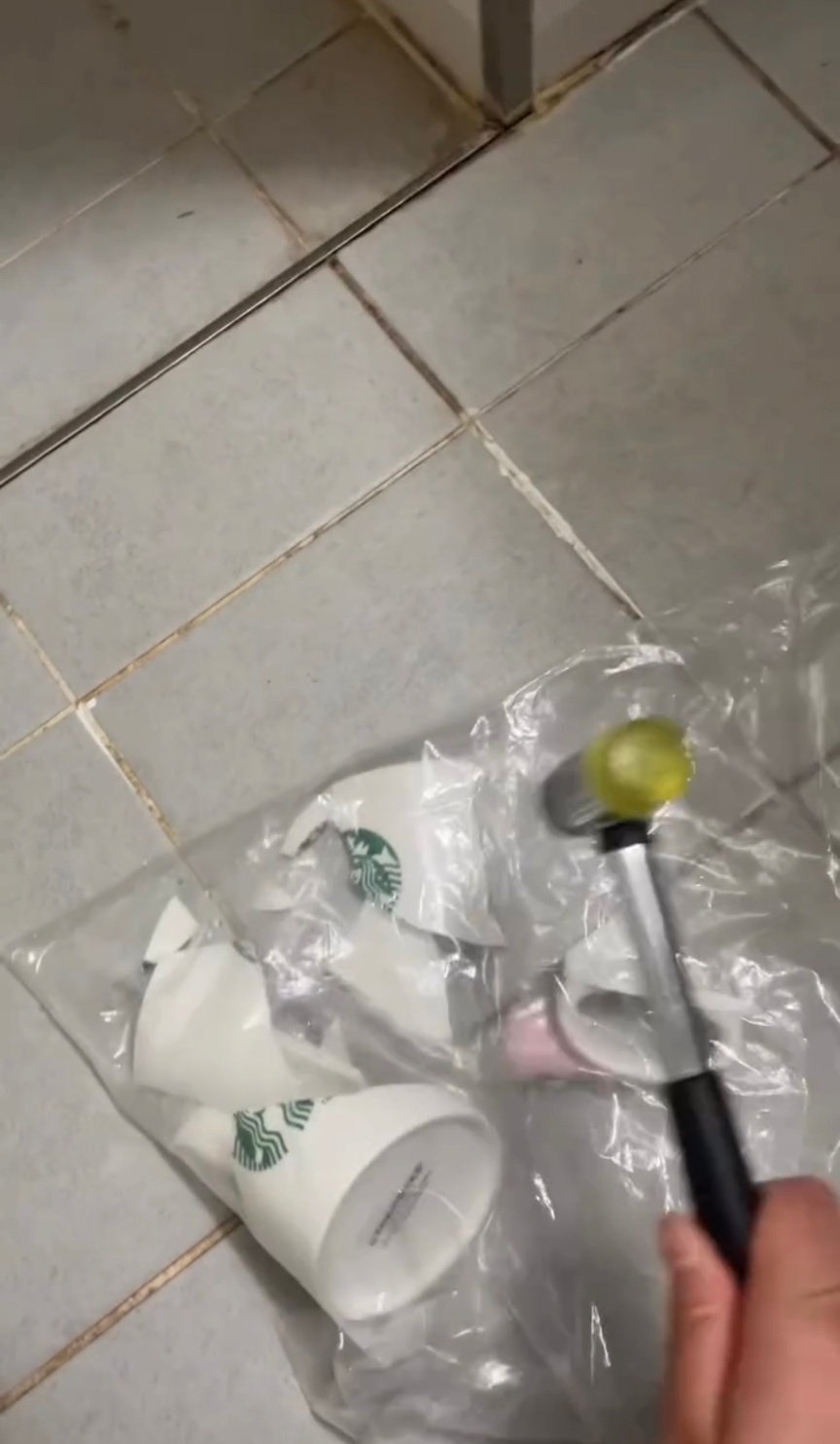 A screenshot from a video posted by an online user shows her smashing a Starbucks mug with a hammer. (Threads)