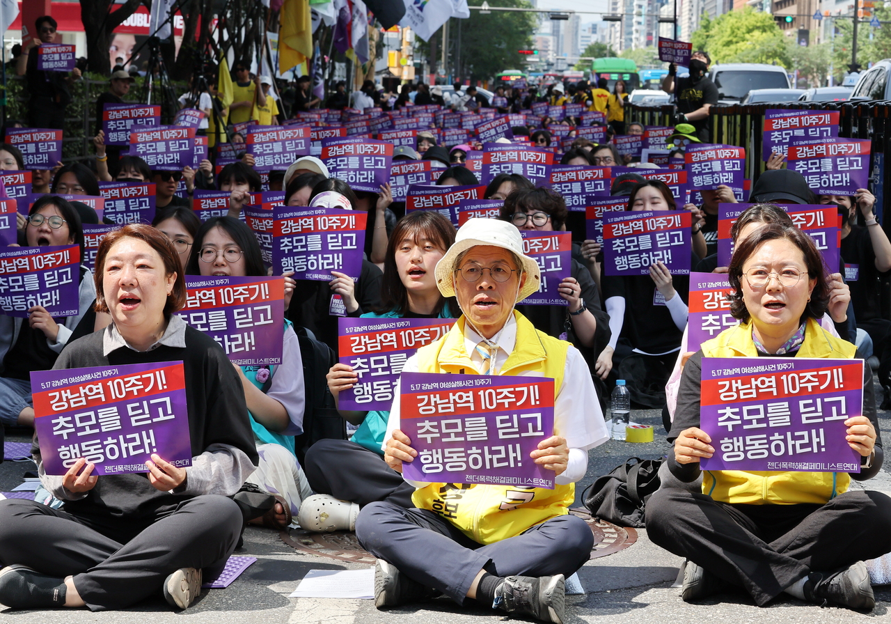 Participants chant slogans while holding placards reading “Gangnam Station, 10 years on: Turn mourning into action,” during a memorial rally held Sunday near Exit 10 of Gangnam Station in Seoul, marking 10 years since a woman was killed near the station. (Yohhap)