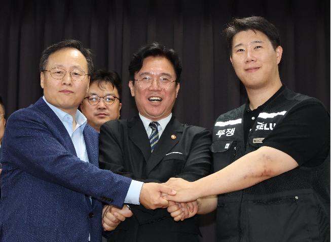 Samsung Electronics DS People Team chief Yeo Myung-gu (left), Labor Minister Kim Young-hoon and union leader Choi Seung-ho clasp hands after signing a tentative wage deal in Suwon, Gyeonggi Province, Wednesday. (Joint Press Corps-)